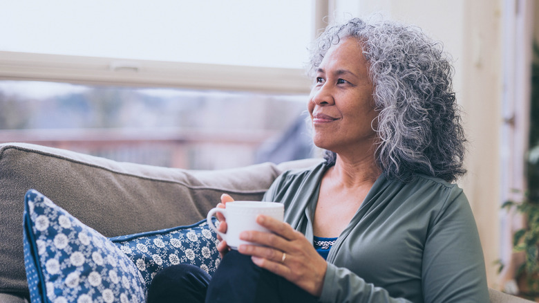woman sitting on her couch drinking tea