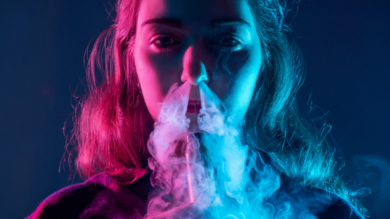 young woman exhaling vape smoke