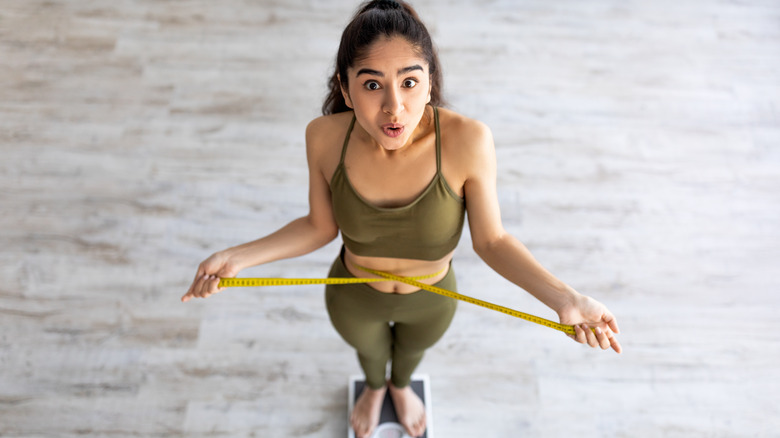 a woman measures her waist 