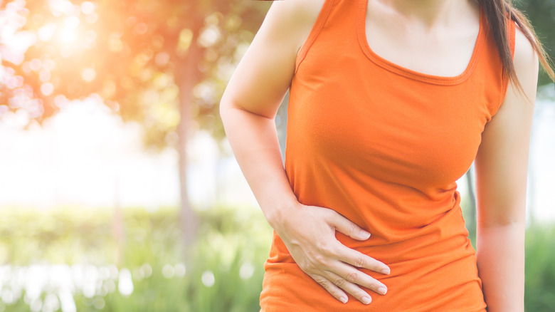 Woman holding stomach outdoors