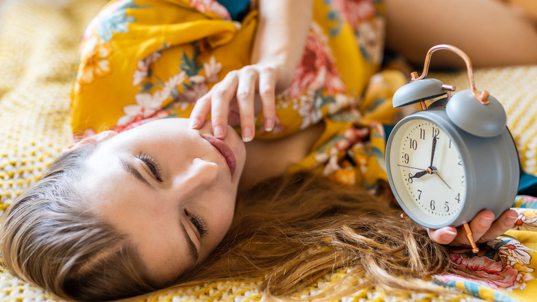 woman laying down next to a small clock