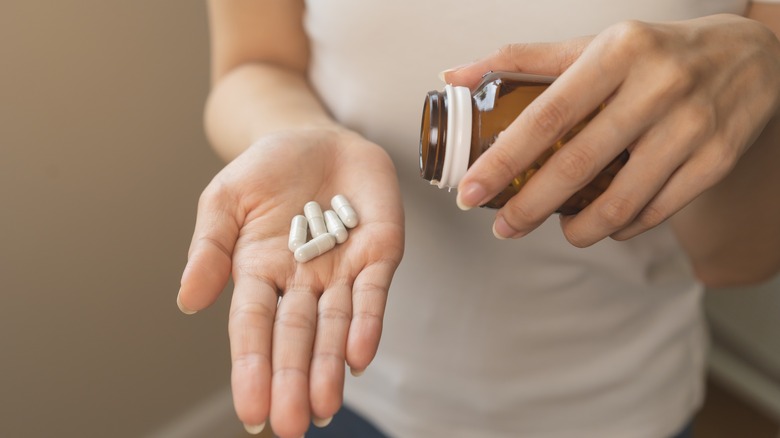 hands pouring vitamin supplement