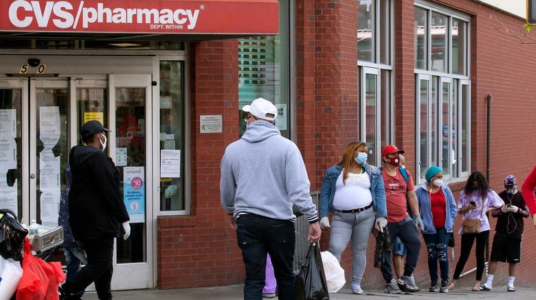 people wait in line outside of a CVS