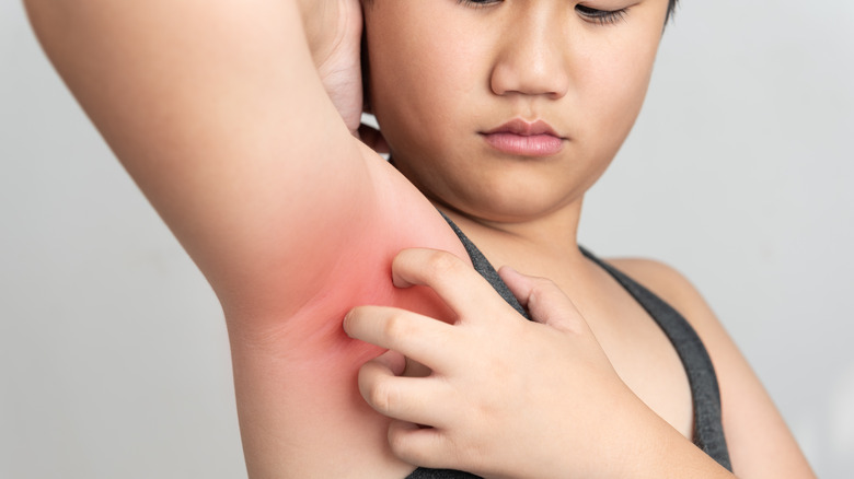 woman using deodorant in armpits