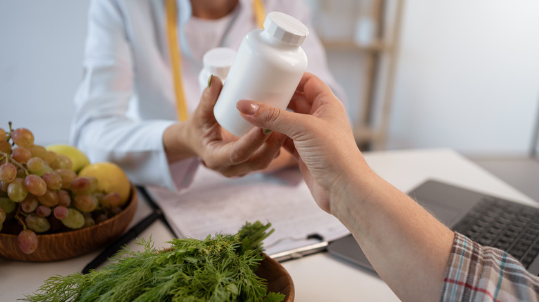 doctor hand close up handing vitamin bottles to patient