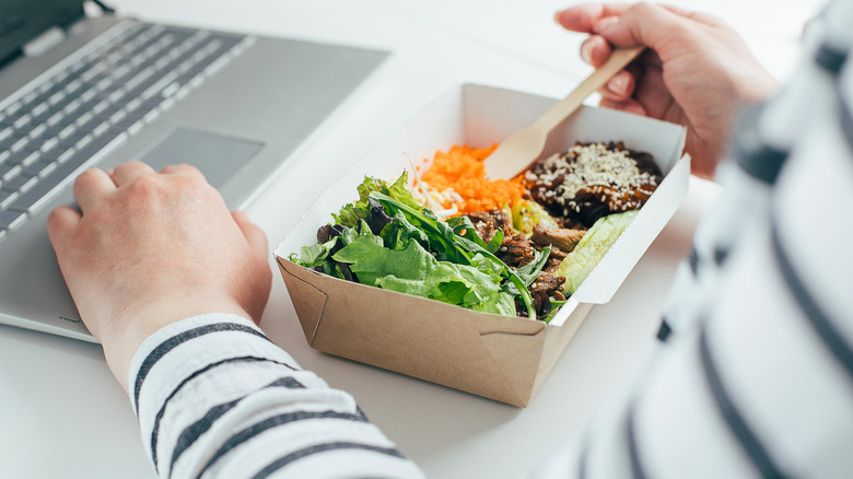 woman eating salad while working