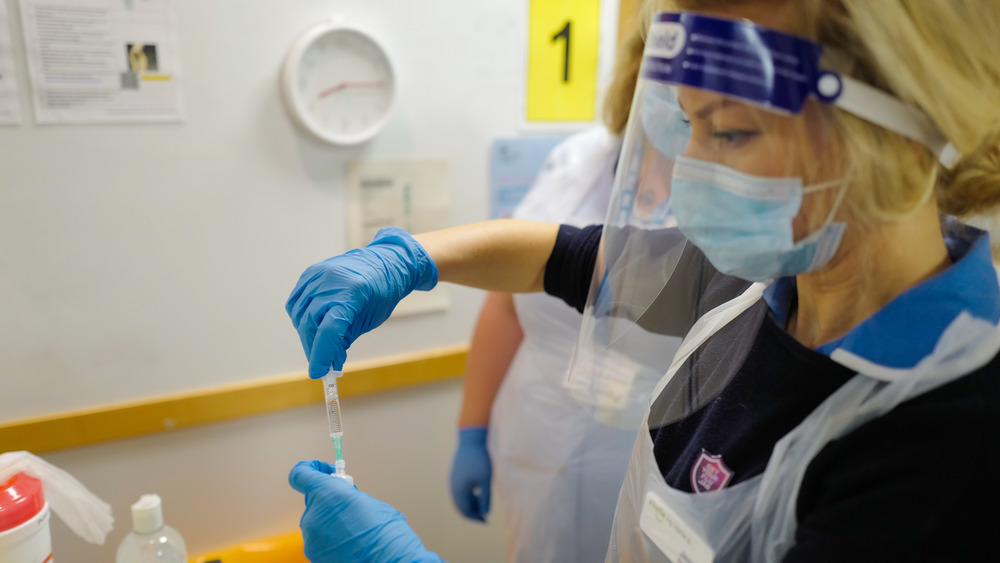 A nurse in England prepares a dose of the COVID-19 vaccine