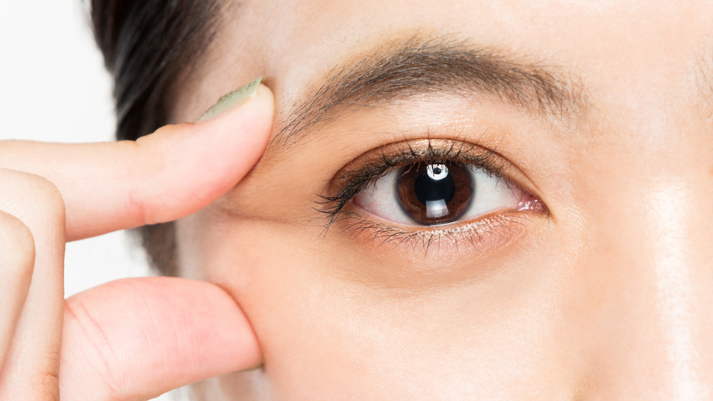 Close-up of woman picking at the corner of her eye