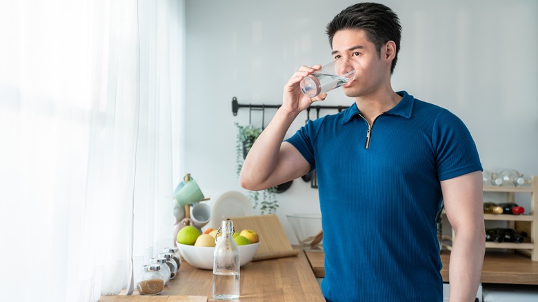 man drinking water in kitchen