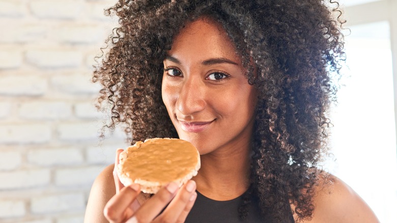 woman eating peanut butter on a rice cake