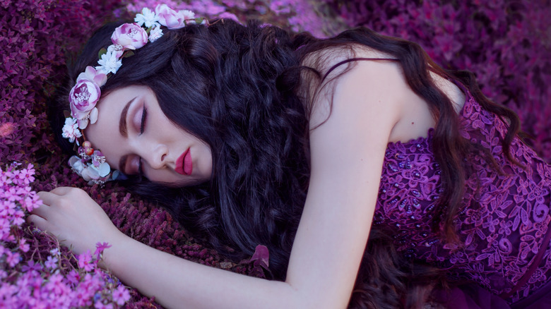 A fair tale princess sleeping on a bed of purple flowers