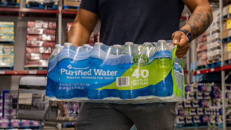A man carries a large package of bottled water