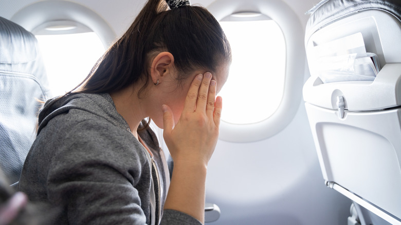 woman on plane touching her face