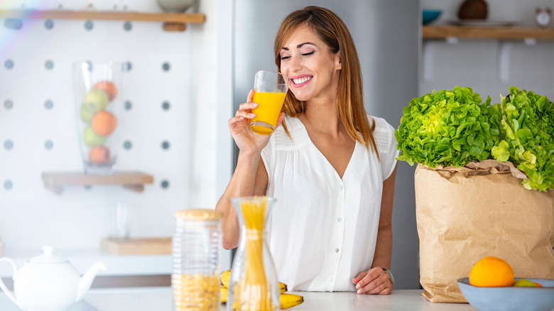 A woman is drinking a glass of orange juice