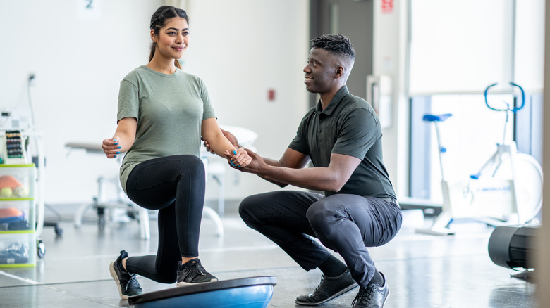 woman lunging on a Bosu ball while working with a physical therapist