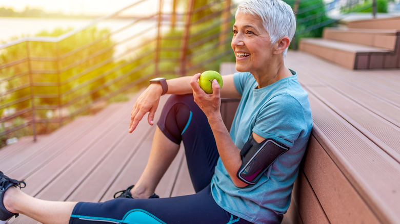 senior woman eating apple after workout