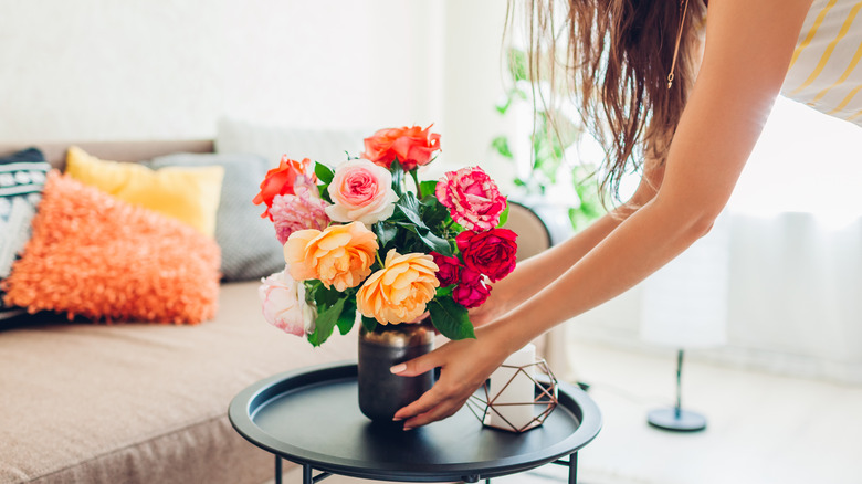 Woman with vase of roses on table