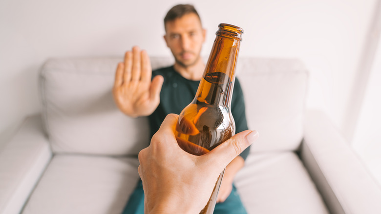 man holding his hand up to say no to a beer
