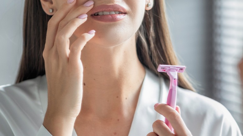 Woman holding razor and touching face