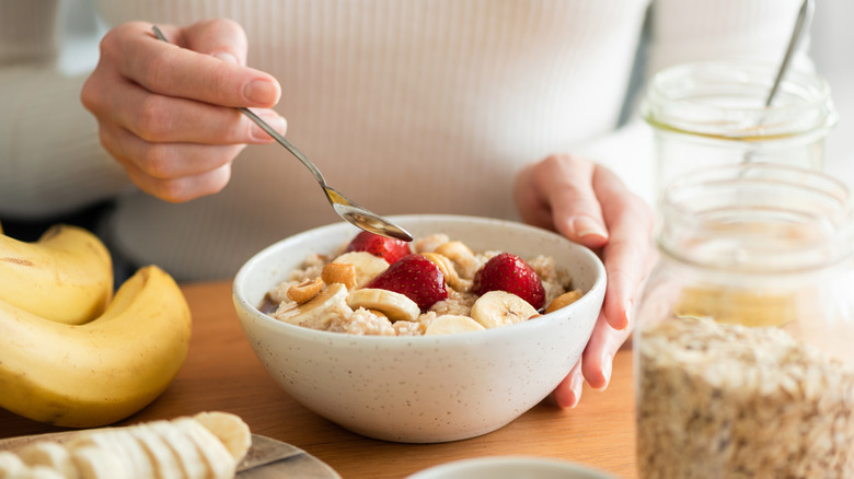 A woman eats oatmeal with bananas in it
