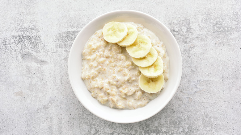 A bowl of oatmeal with sliced bananas on top