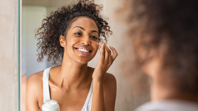 A woman is moisturizing her face