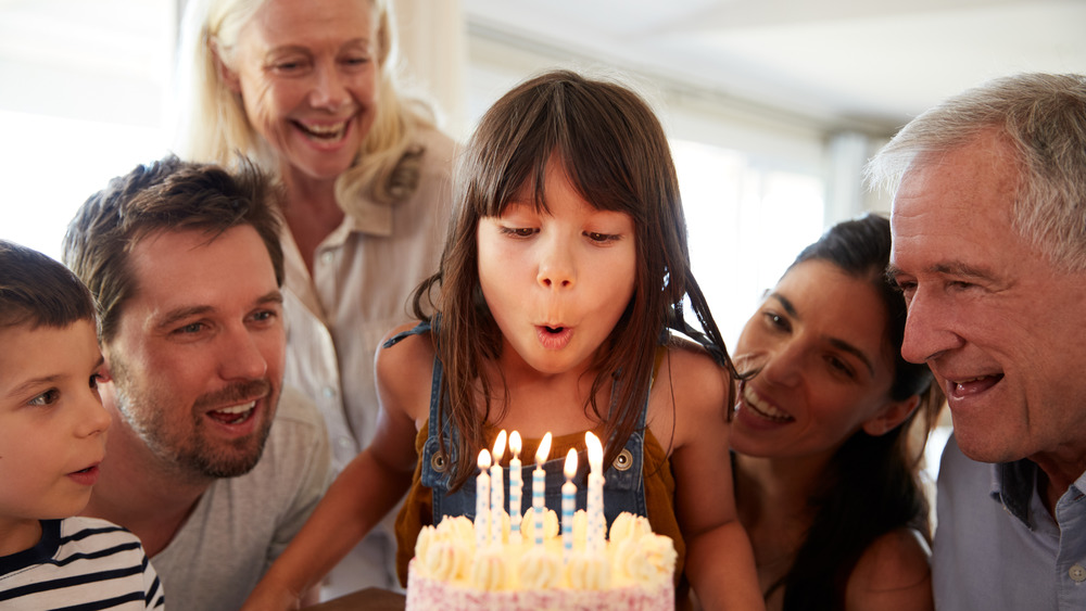 Girl and family blow candles