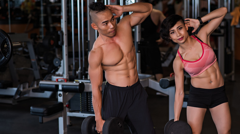 A man and woman perform dumbbell side bends