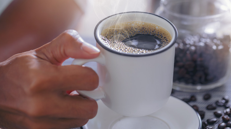 woman's hand holding a hot cup of coffee 