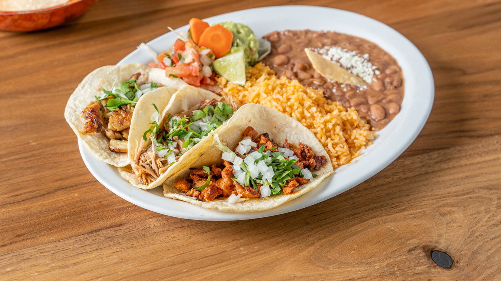 Mexican meal with rice, refried beans, and tacos on a plate