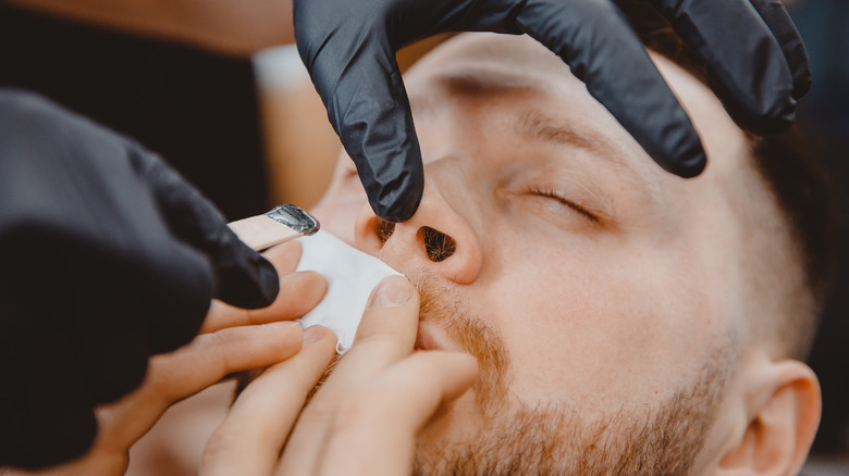 Man undergoing professional nose hair waxing