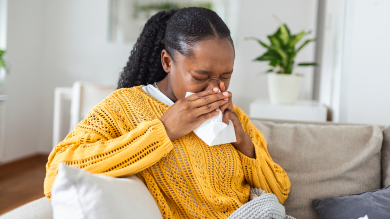 Woman blowing nose into tissue