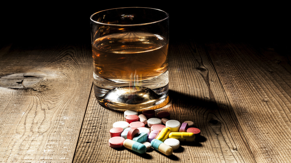 Alcohol in glass with pills in foreground