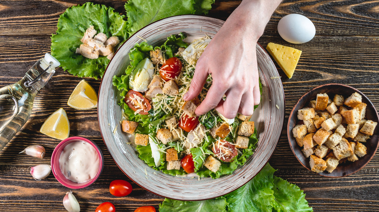 Someone is placing a crouton in a bowl of salad