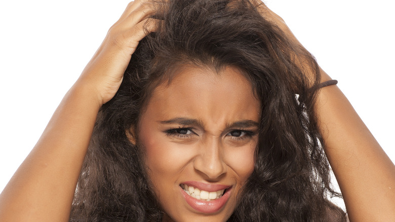 young woman with long hair scratching scalp