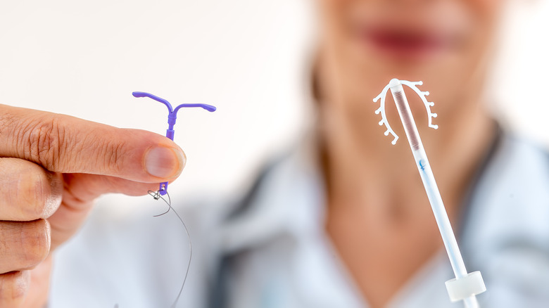 A doctor holds two types of IUDs