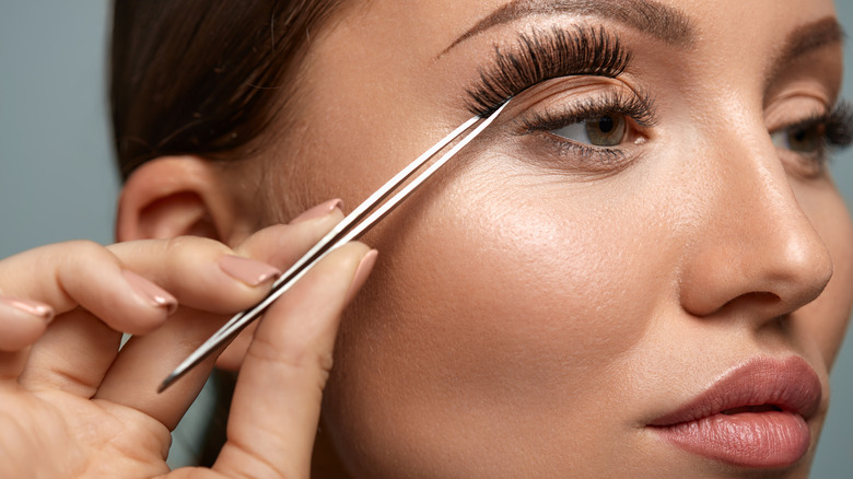 A woman applies fake eyelashes
