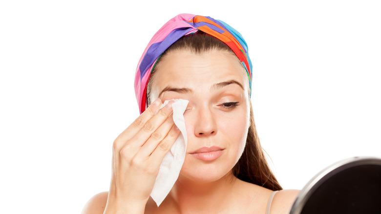 woman cleaning face with makeup wipes