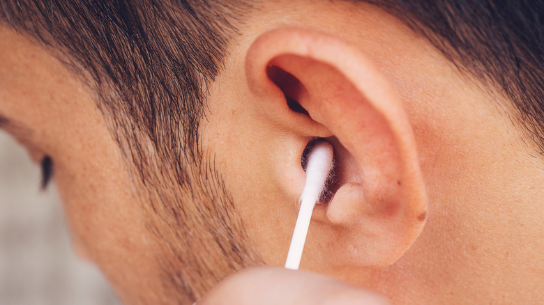 man cleaning ears with q-tip
