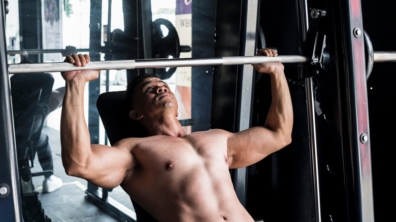 A man uses a Smith machine to lift a barbell over his head