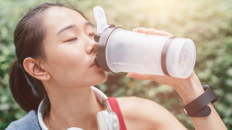 Asian woman drinking from water bottle