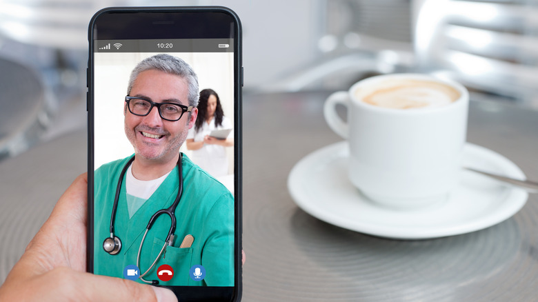 A smiling doctor on Facetime with a coffee in the background 
