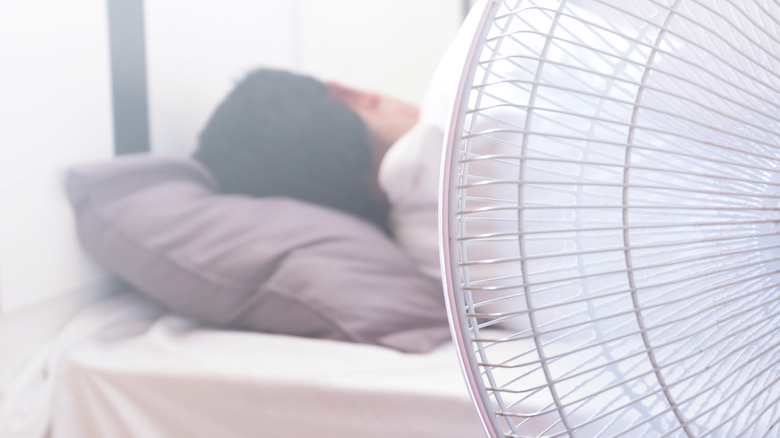 Person turned away while asleep with a fan blowing on them