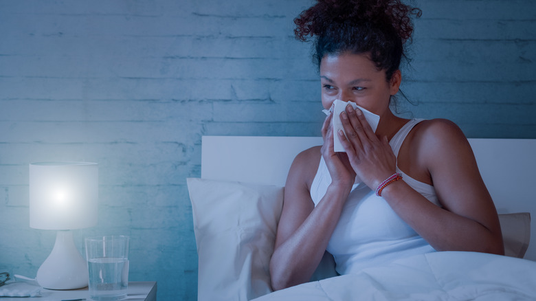 woman blowing her nose in bed