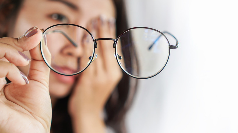 Woman holding pair of glasses