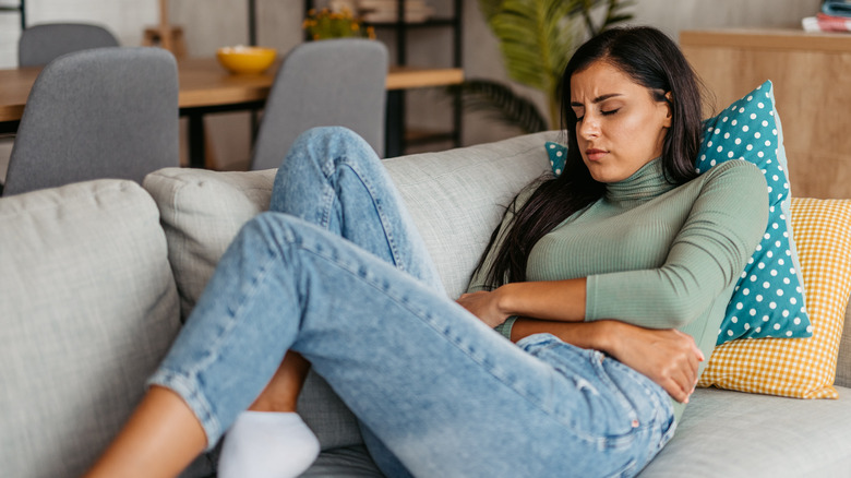 woman lying on sofa with an upset stomach