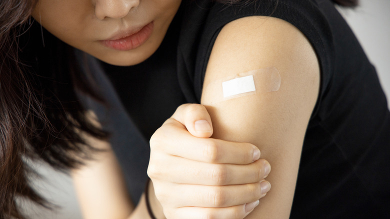 young woman holding her arm by her vaccine injection site 