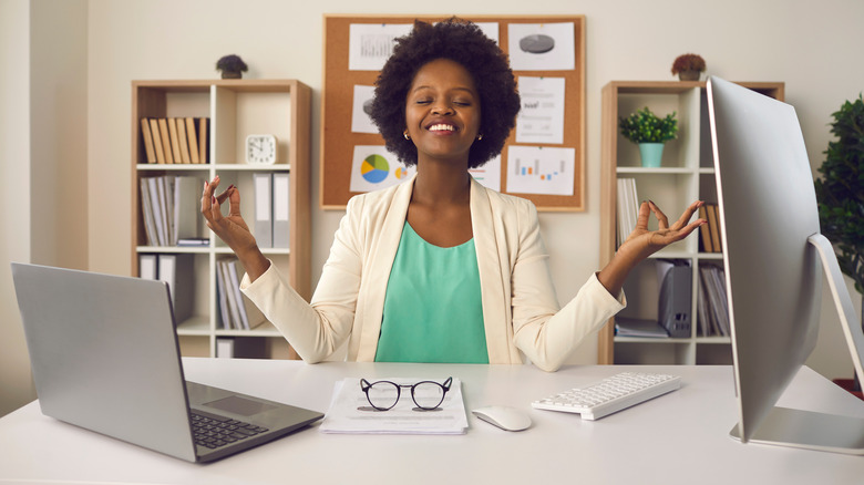 Smiling woman meditating at desk