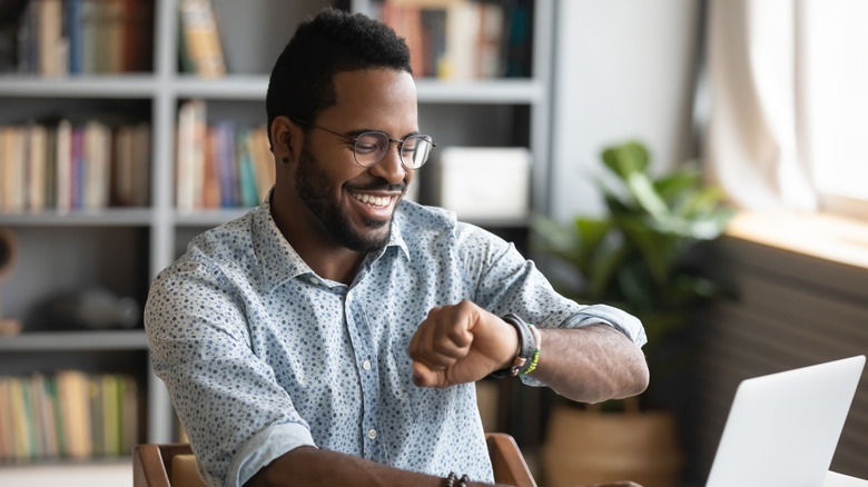 Man at desk smiling at fitness tracker