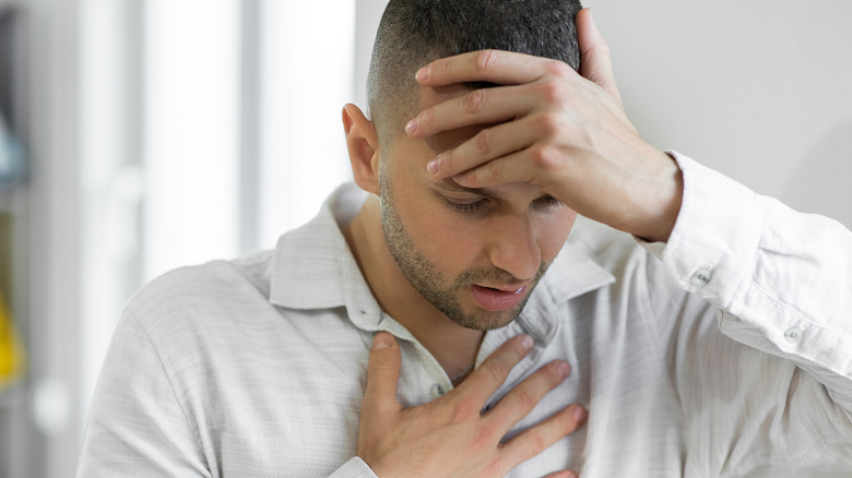 Man touching head and chest in pain